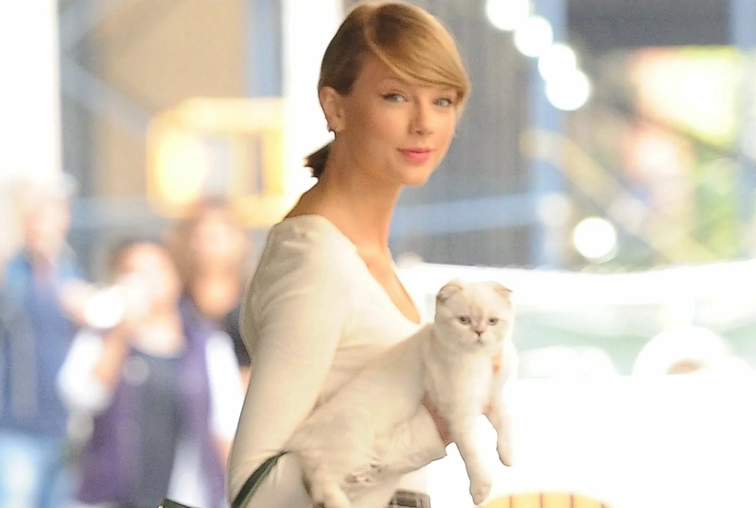 Taylor Swift hält eine weiße Katze in der Hand, während sie die Straße entlang geht